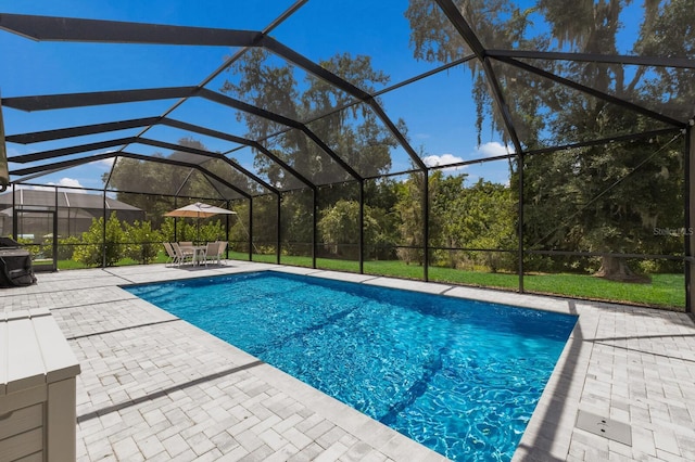 view of pool with glass enclosure, a patio area, and a yard