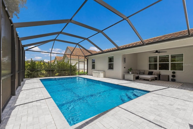 view of pool with glass enclosure, a patio area, outdoor lounge area, and ceiling fan