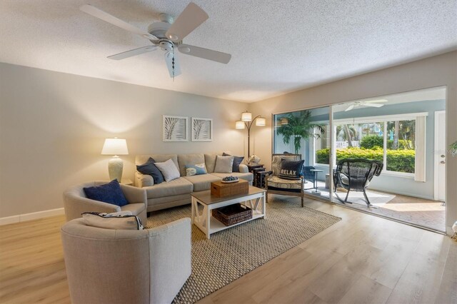 living room featuring ceiling fan, light hardwood / wood-style floors, and a textured ceiling