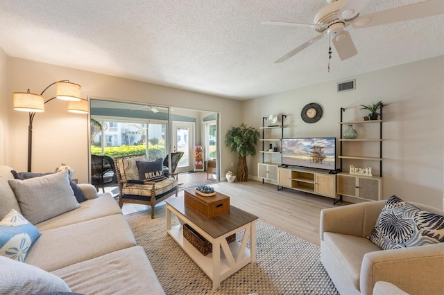 living room with ceiling fan, light hardwood / wood-style floors, and a textured ceiling