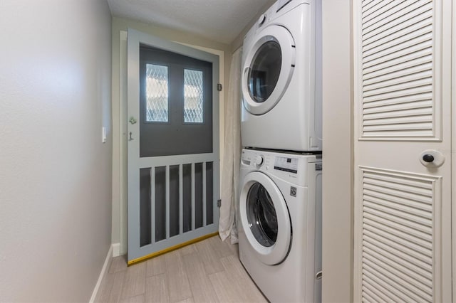 washroom featuring a textured ceiling, light hardwood / wood-style floors, and stacked washer and clothes dryer