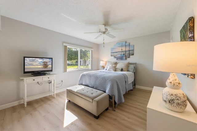 bedroom with ceiling fan, light wood-type flooring, and a textured ceiling