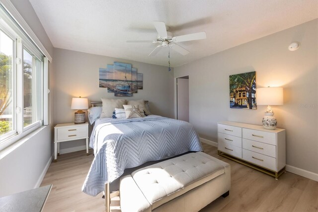 bedroom with ceiling fan, light wood-type flooring, and multiple windows