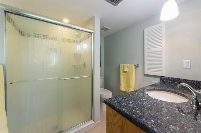 bathroom featuring vanity, toilet, and a shower with door