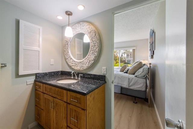 bathroom with hardwood / wood-style floors, vanity, and a textured ceiling