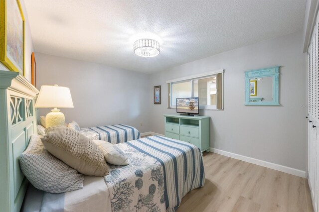 bedroom with light wood-type flooring and a textured ceiling