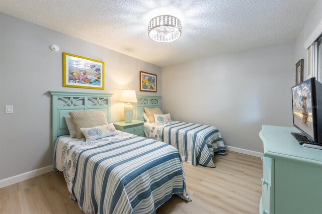 bedroom featuring a textured ceiling and light hardwood / wood-style flooring