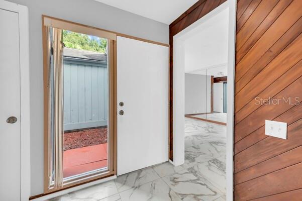 doorway featuring marble finish floor and wood walls