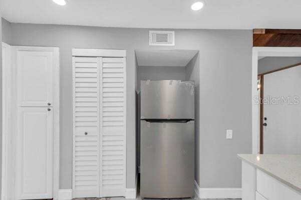 1502 NE Buckeye Rd NE Unit 2, Winter Haven, FL 33881 - kitchen featuring light countertops, visible vents, freestanding refrigerator, white cabinets, and baseboards