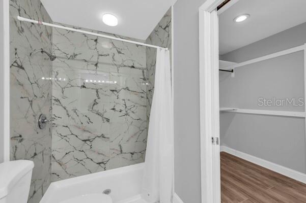 1502 NE Buckeye Rd NE Unit 2, Winter Haven, FL 33881 - full bathroom with toilet, a stall shower, baseboards, and wood finished floors