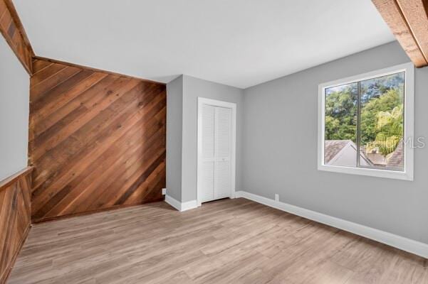 1502 NE Buckeye Rd NE Unit 2, Winter Haven, FL 33881 - unfurnished bedroom featuring wood walls, light wood-type flooring, a closet, and baseboards