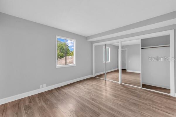 1502 NE Buckeye Rd NE Unit 2, Winter Haven, FL 33881 - unfurnished bedroom featuring wood finished floors, two closets, and baseboards