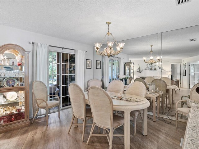 dining room with a textured ceiling, a notable chandelier, and wood-type flooring