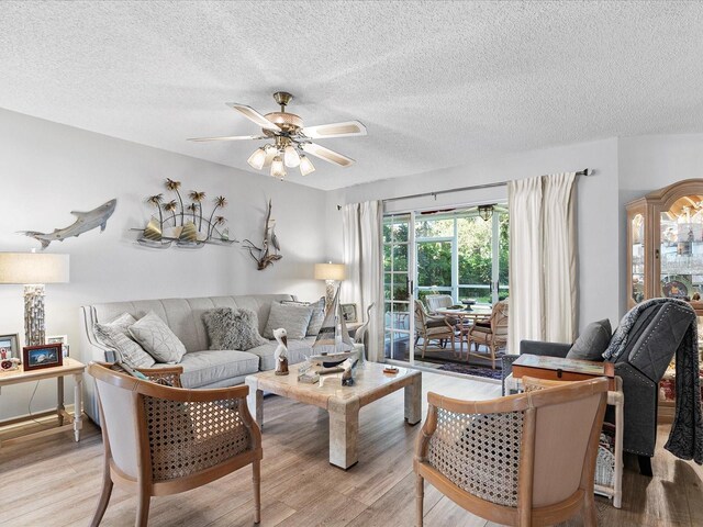 living room featuring a textured ceiling, ceiling fan, and light wood-type flooring