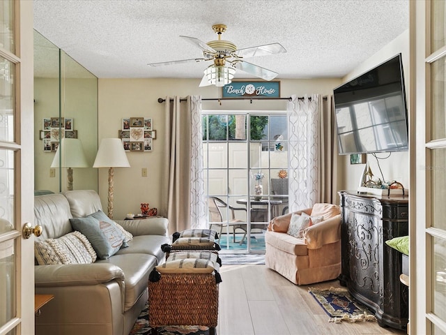 living room with hardwood / wood-style floors, ceiling fan, and a textured ceiling