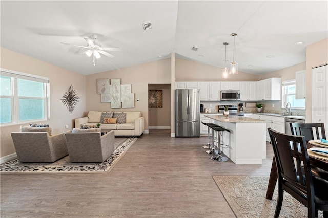 living room featuring vaulted ceiling, sink, hardwood / wood-style floors, and ceiling fan