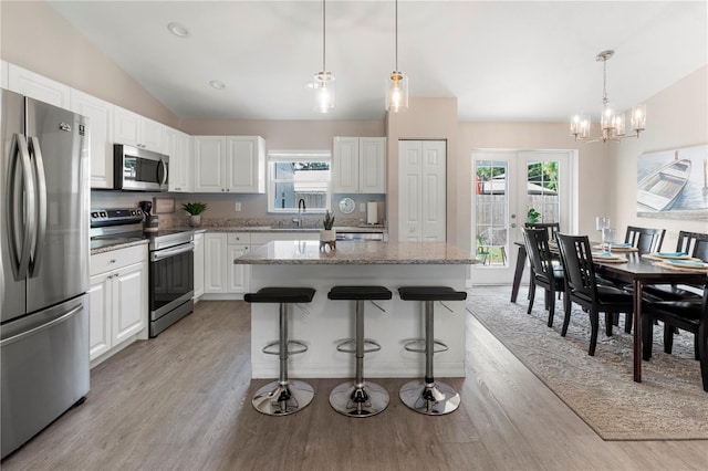 kitchen with light stone countertops, white cabinetry, appliances with stainless steel finishes, and a center island