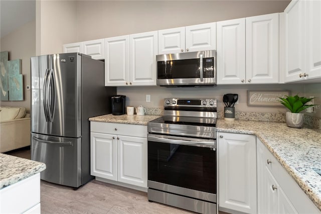 kitchen featuring light stone countertops, white cabinetry, appliances with stainless steel finishes, and light hardwood / wood-style floors