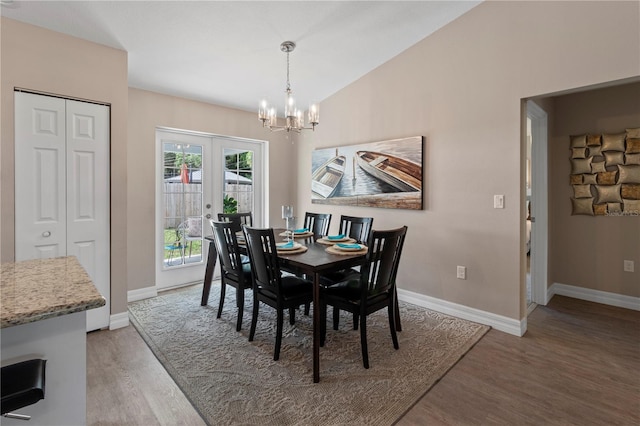 dining space with hardwood / wood-style flooring, lofted ceiling, a notable chandelier, and french doors