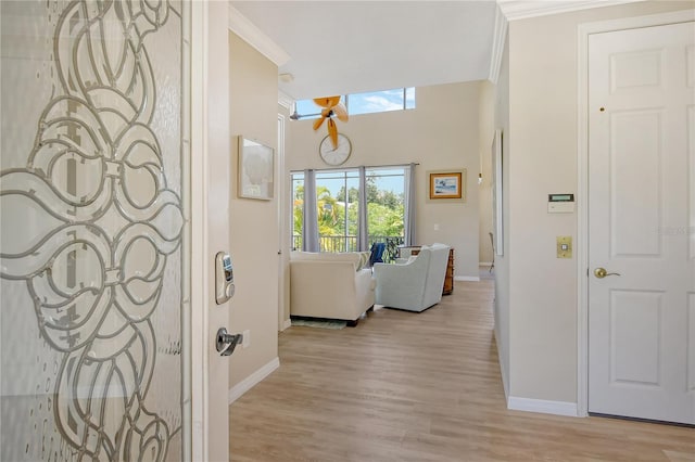 corridor with light hardwood / wood-style floors and ornamental molding