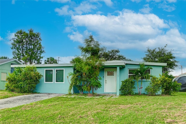 view of front of house featuring driveway, a front lawn, and stucco siding