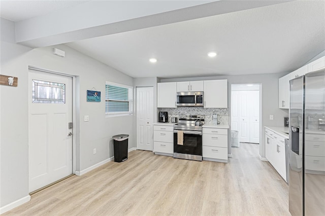 kitchen featuring light wood finished floors, appliances with stainless steel finishes, light countertops, white cabinetry, and backsplash