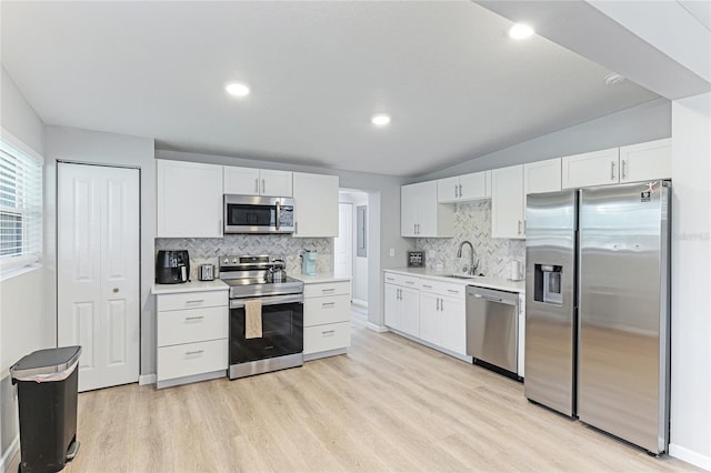 kitchen featuring stainless steel appliances, a sink, white cabinetry, light countertops, and light wood-type flooring