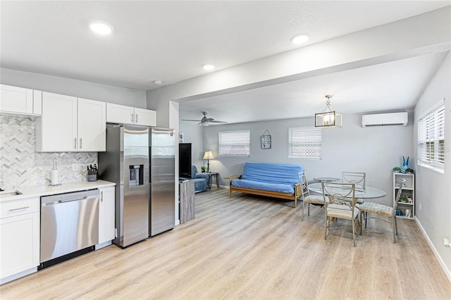 kitchen with appliances with stainless steel finishes, light countertops, white cabinetry, and a wall unit AC