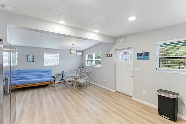 interior space with a textured ceiling, light wood-style flooring, recessed lighting, baseboards, and vaulted ceiling