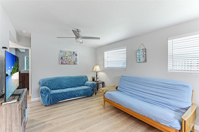 living room featuring a ceiling fan, a healthy amount of sunlight, a textured ceiling, and light wood finished floors