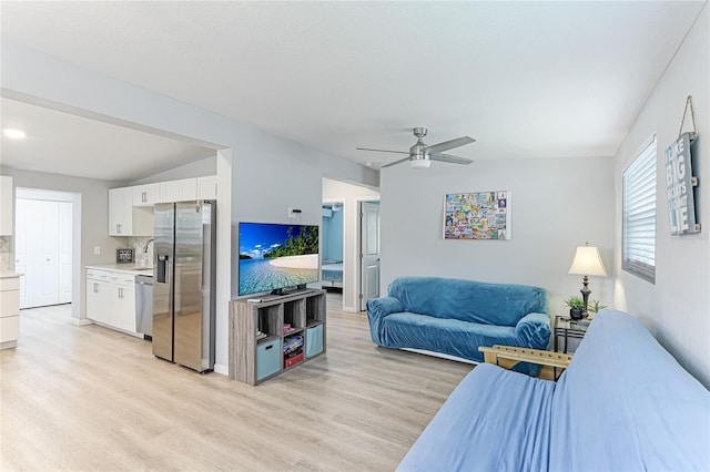 living room featuring vaulted ceiling, light wood finished floors, and ceiling fan