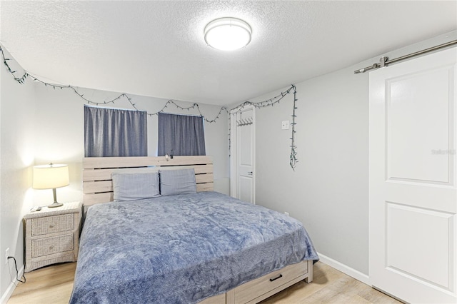 bedroom featuring a textured ceiling, wood finished floors, and baseboards