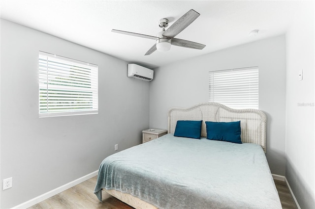 bedroom with light wood finished floors, a wall mounted air conditioner, and baseboards