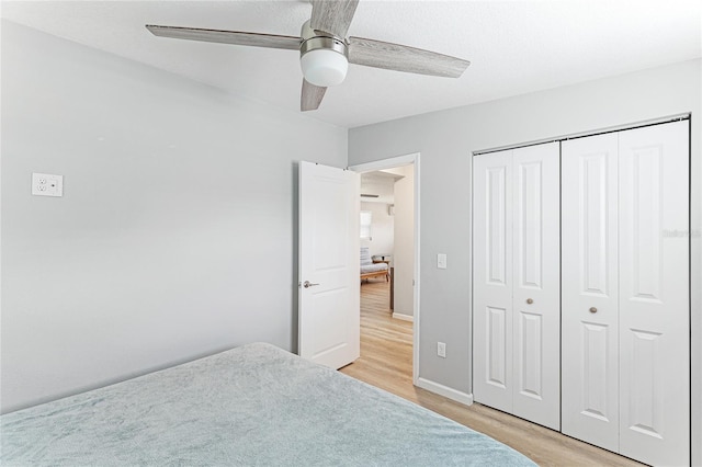 unfurnished bedroom featuring light wood-style floors, a closet, ceiling fan, and baseboards