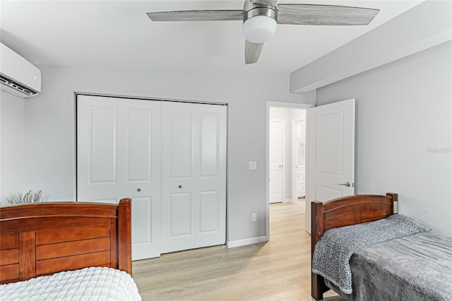 bedroom featuring light wood finished floors, baseboards, a ceiling fan, a wall unit AC, and a closet