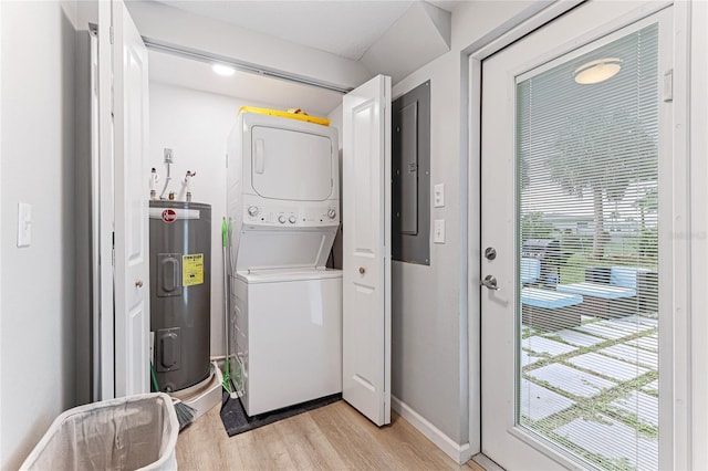 washroom featuring stacked washer / drying machine, water heater, light wood-style flooring, laundry area, and electric panel