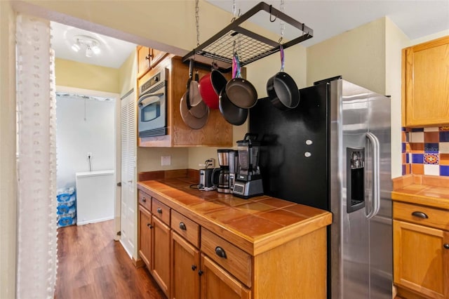 kitchen featuring tile counters, dark hardwood / wood-style floors, decorative backsplash, and stainless steel refrigerator with ice dispenser