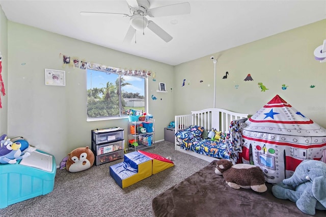 carpeted bedroom featuring ceiling fan and a nursery area