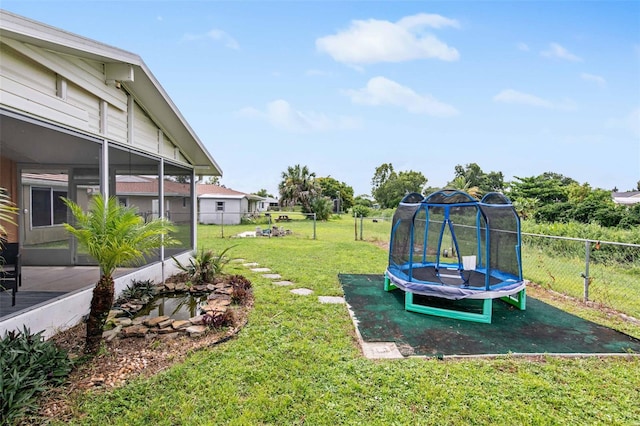 view of yard with a sunroom and a trampoline