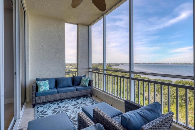 sunroom featuring a wealth of natural light, ceiling fan, and a water view