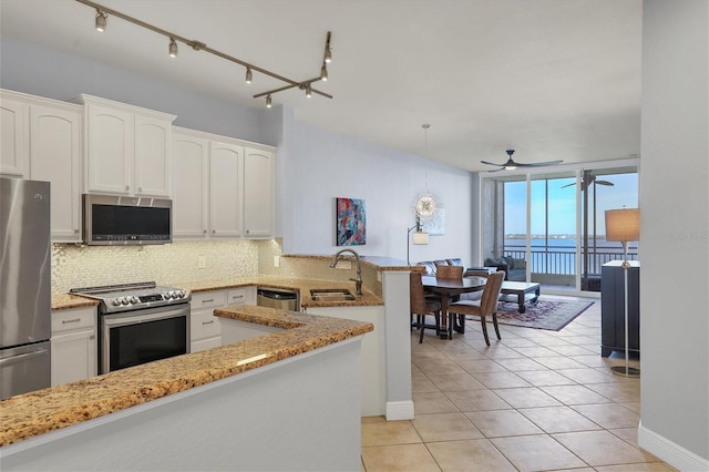 kitchen featuring stainless steel appliances, a peninsula, a water view, white cabinetry, and backsplash