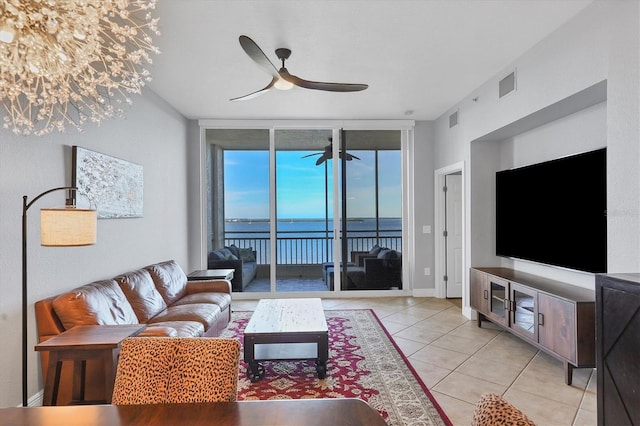 living area with light tile patterned floors, visible vents, a wall of windows, and a ceiling fan