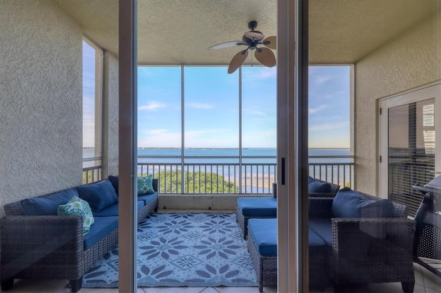 sunroom with a ceiling fan and a water view