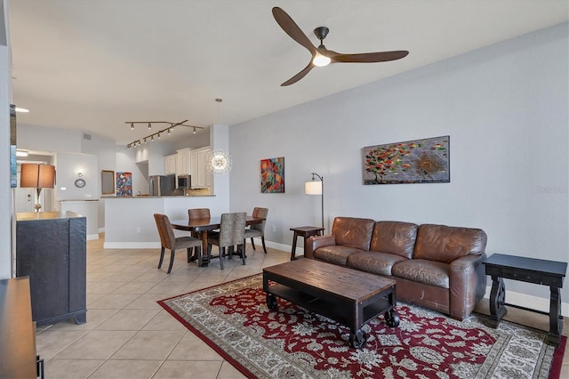 living area featuring ceiling fan, track lighting, light tile patterned flooring, and baseboards