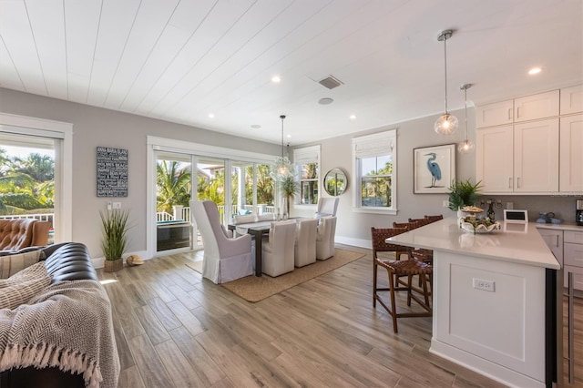 interior space with light hardwood / wood-style flooring, pendant lighting, white cabinets, and a breakfast bar