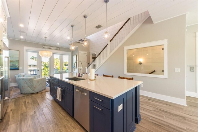 kitchen with dishwasher, sink, blue cabinetry, an island with sink, and light wood-type flooring