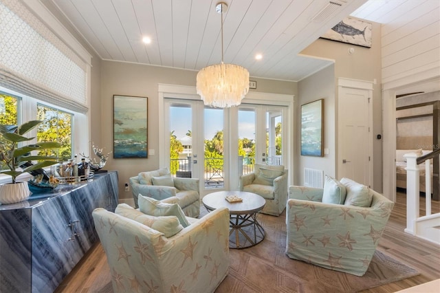 living room featuring crown molding, hardwood / wood-style floors, an inviting chandelier, and french doors