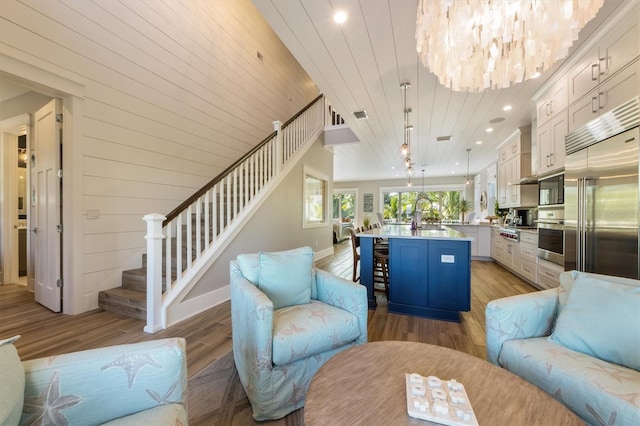 living room with sink, a chandelier, and light wood-type flooring