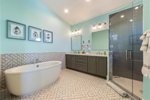 bathroom featuring plus walk in shower, double vanity, tile patterned flooring, and tile walls