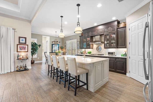 kitchen with a center island with sink, dark brown cabinetry, and light hardwood / wood-style floors